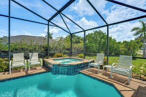 A swimming pool with a hot tub, surrounded by a covered area with chairs. - 3 Mi to Fort Myers Beach! Family Getaway w/ Pool (Fort Myers)