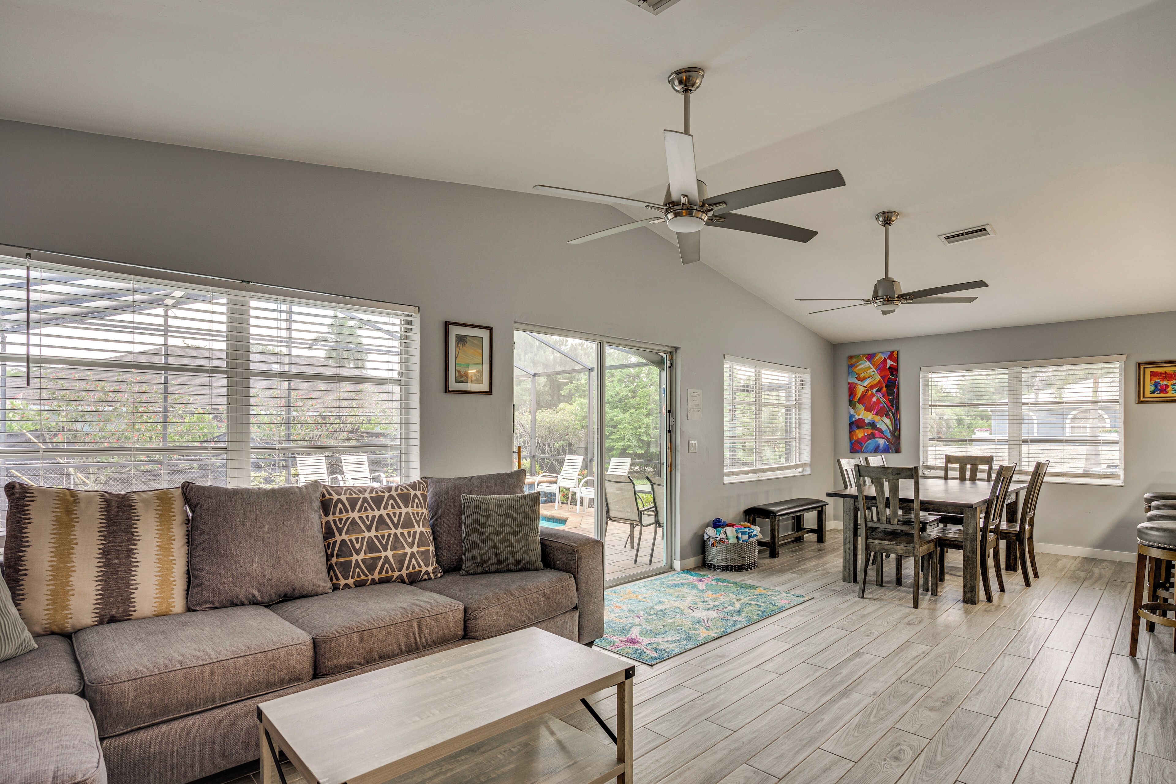 A spacious living area with a sofa, coffee table, dining table, chairs, and ceiling fans.