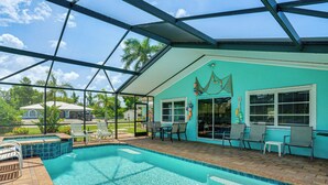 Une piscine extérieure couverte, dotée d’un toit en verre, entourée de chaises longues et d’un espace patio.