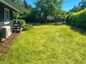 A residential backyard with a lawn, a wooden deck, and a house.
