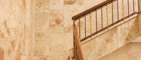 A marble staircase with a wooden handrail and a wall with a similar marble pattern.