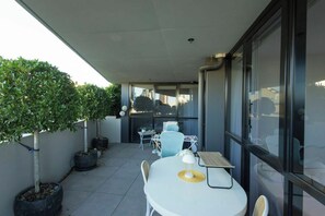 Eine moderne Außenpatio mit einem runden Tisch, Stühlen und einem Blumentopf-Baum.