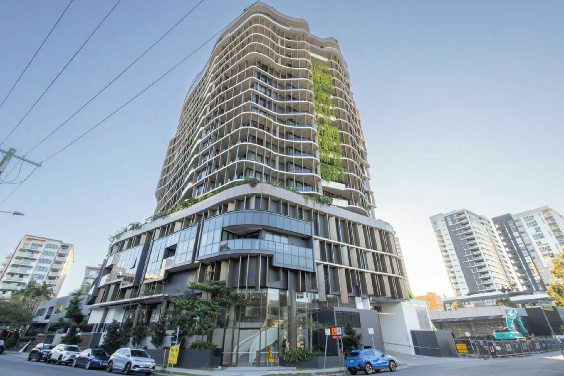 Ein modernes Hochhaus mit geschwungener Fassade, mehreren Balkonen und einer Mischung aus Glas- und Betonmaterialien.