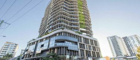 Un moderno edificio de gran altura con fachada curva, varios balcones y una combinación de materiales de vidrio y hormigón.