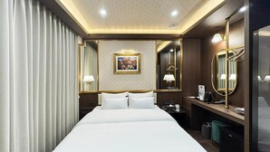 A hotel room with a large bed, a desk with a telephone, a mirror, and a painting on the wall. - HotelArena514 (Seoul)