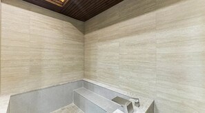 Une salle de bain avec une baignoire intégrée, des murs carrelés et un plafond en bois.