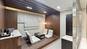 A modern hotel room with a wooden accent wall, a small seating area with a table, and a glass partition. - HotelArena514 (Seoul)