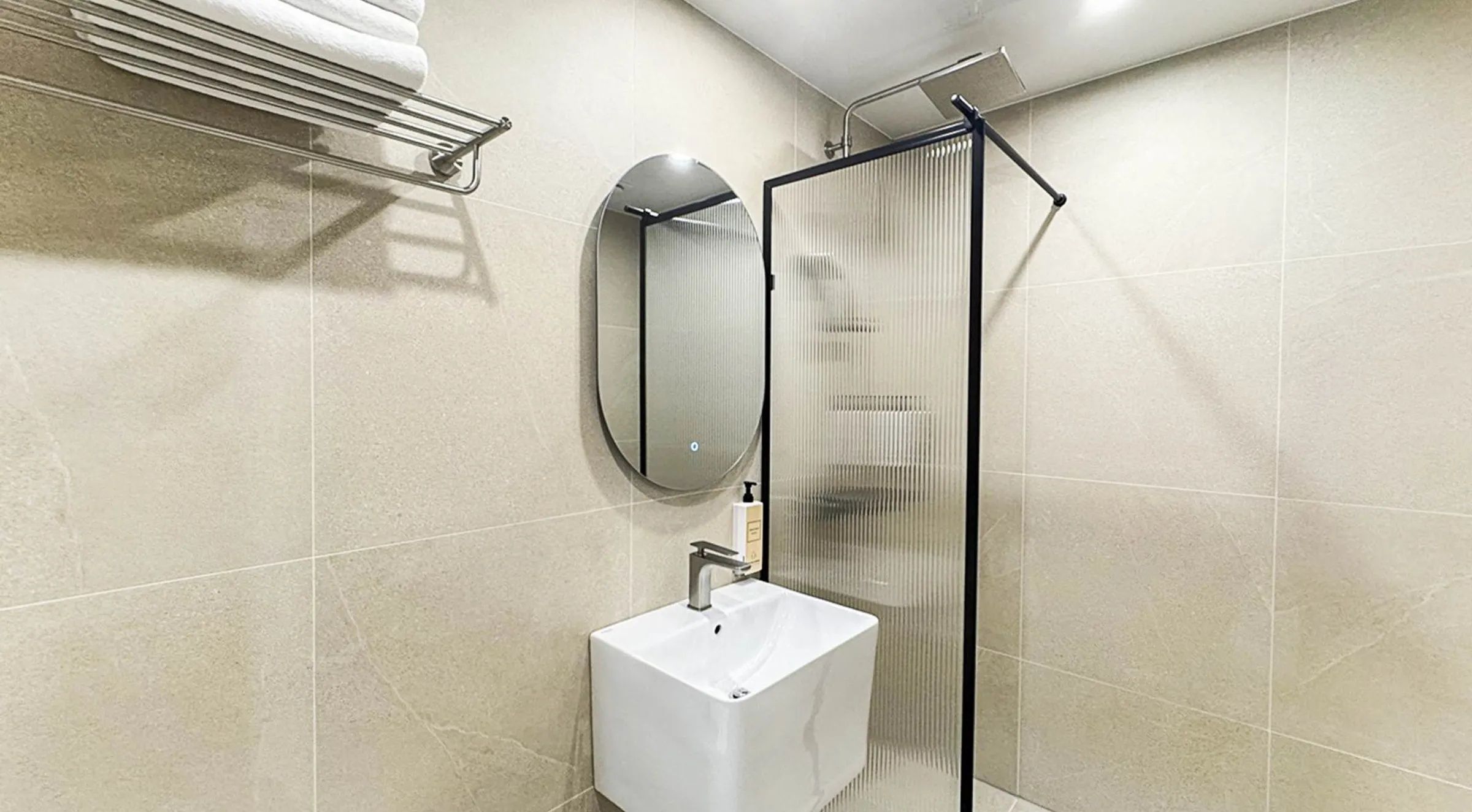A modern bathroom with a white sink, a mirror, and a glass shower enclosure.