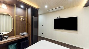 Une chambre d’hôtel équipée d’un lit, d’un bureau avec un ordinateur, d’un miroir et d’un téléviseur à écran plat fixé au mur.