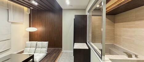 A modern interior with a seating area, a dark accent wall, and a glass partition.