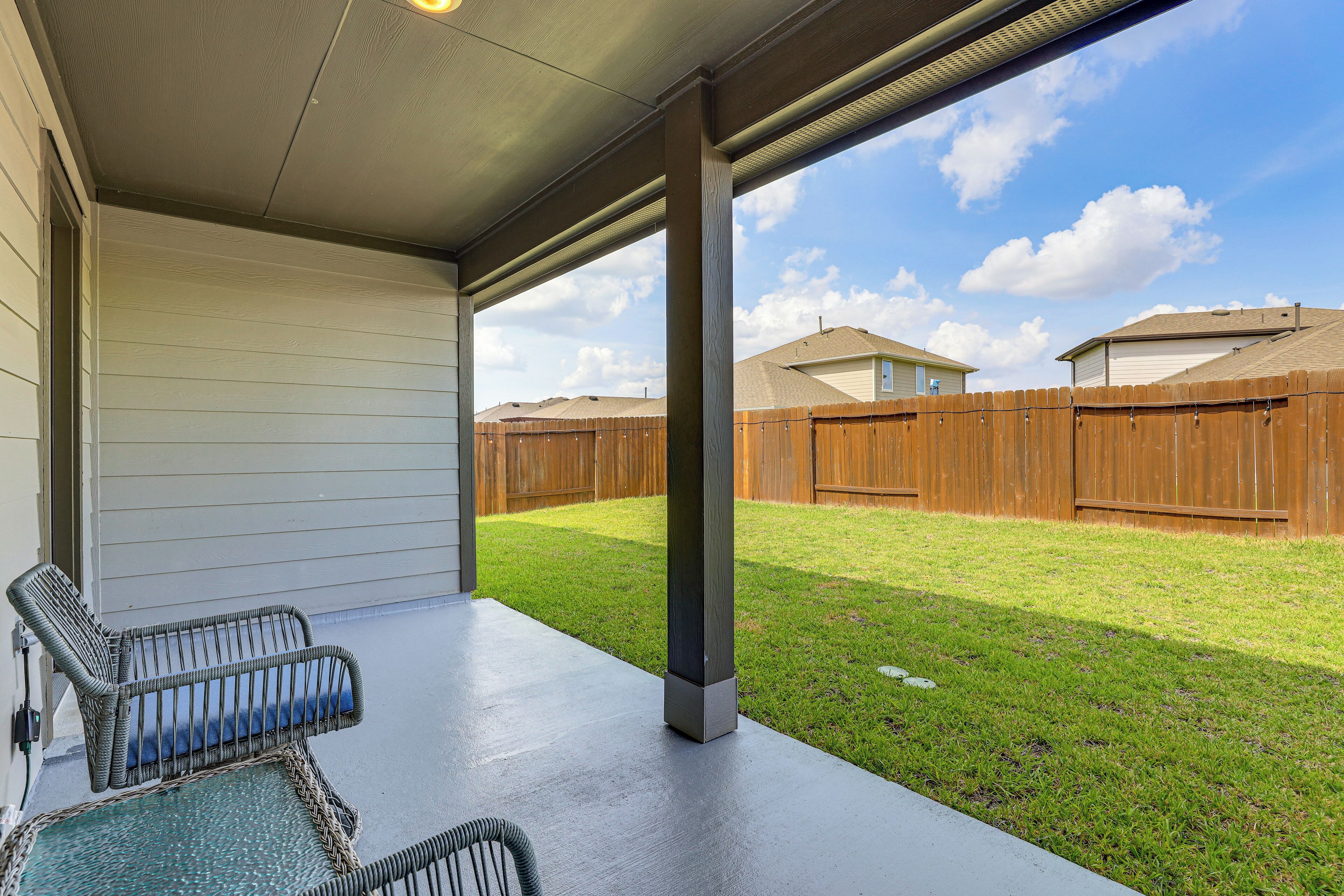 A covered patio area with two wicker chairs and a concrete floor.