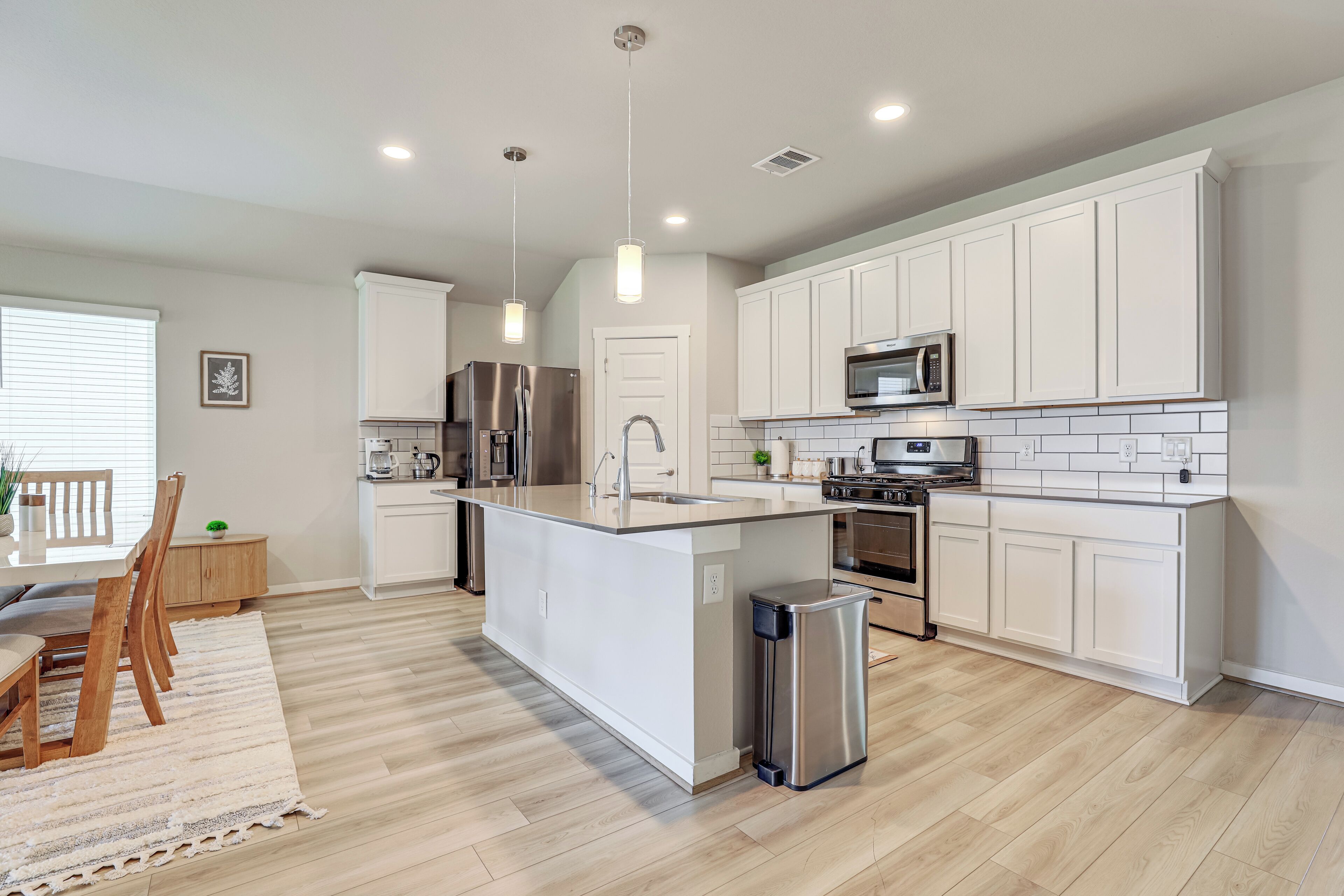A modern kitchen with white cabinetry, stainless steel appliances, and a central island.