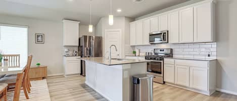 A modern kitchen with white cabinetry, stainless steel appliances, and a central island.