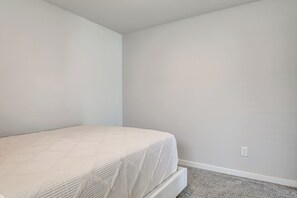 Ein schlichter, kleiner Raum mit einem Bett und Teppichboden.