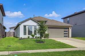 A single-story residential house with a garage, a small front yard with grass and a young tree, and a clear blue sky. - Work & Explore! Sleek Richmond Home w/ Pool Access (Richmond)