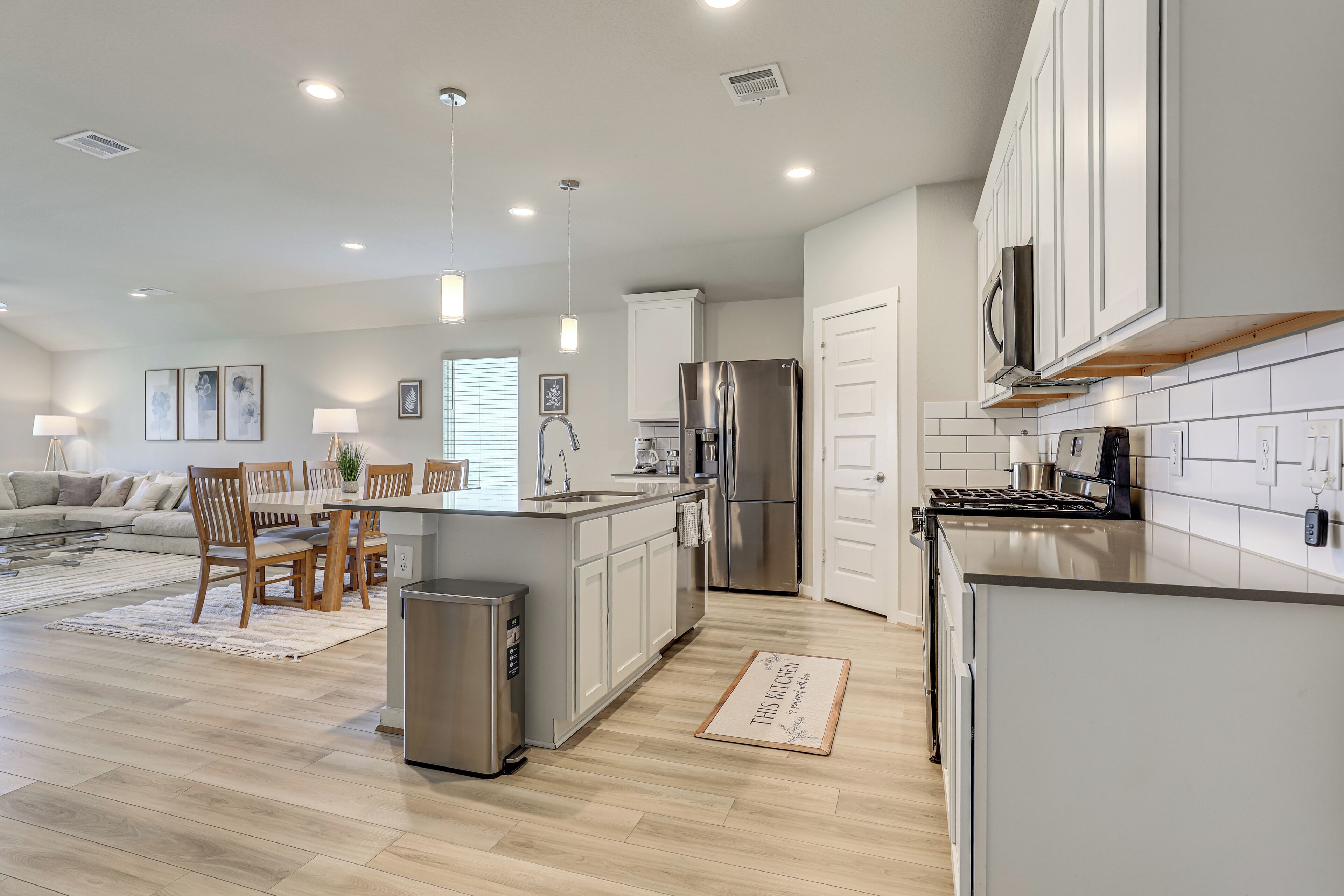 A modern kitchen with a central island, stainless steel appliances, and a dining area with a sofa and chairs.