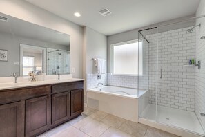 A modern bathroom with a glass-enclosed shower, a freestanding bathtub, and a vanity with a large mirror. - Work & Explore! Sleek Richmond Home w/ Pool Access (Richmond)