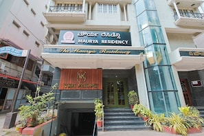 A hotel entrance with a sign for 'Maurya Residency' and a wooden sign for 'VG Kourt'. - Hotel Maurya Residency (Mysore)