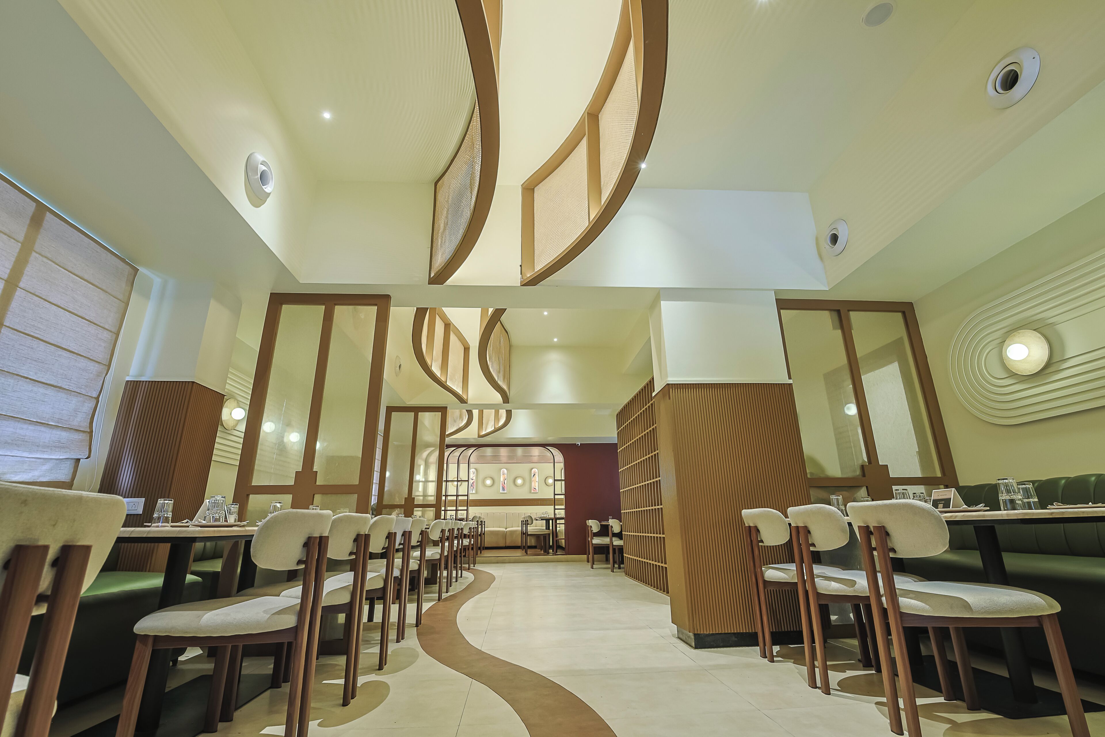 A modern restaurant interior with a central walkway, wooden chairs, and tables.
