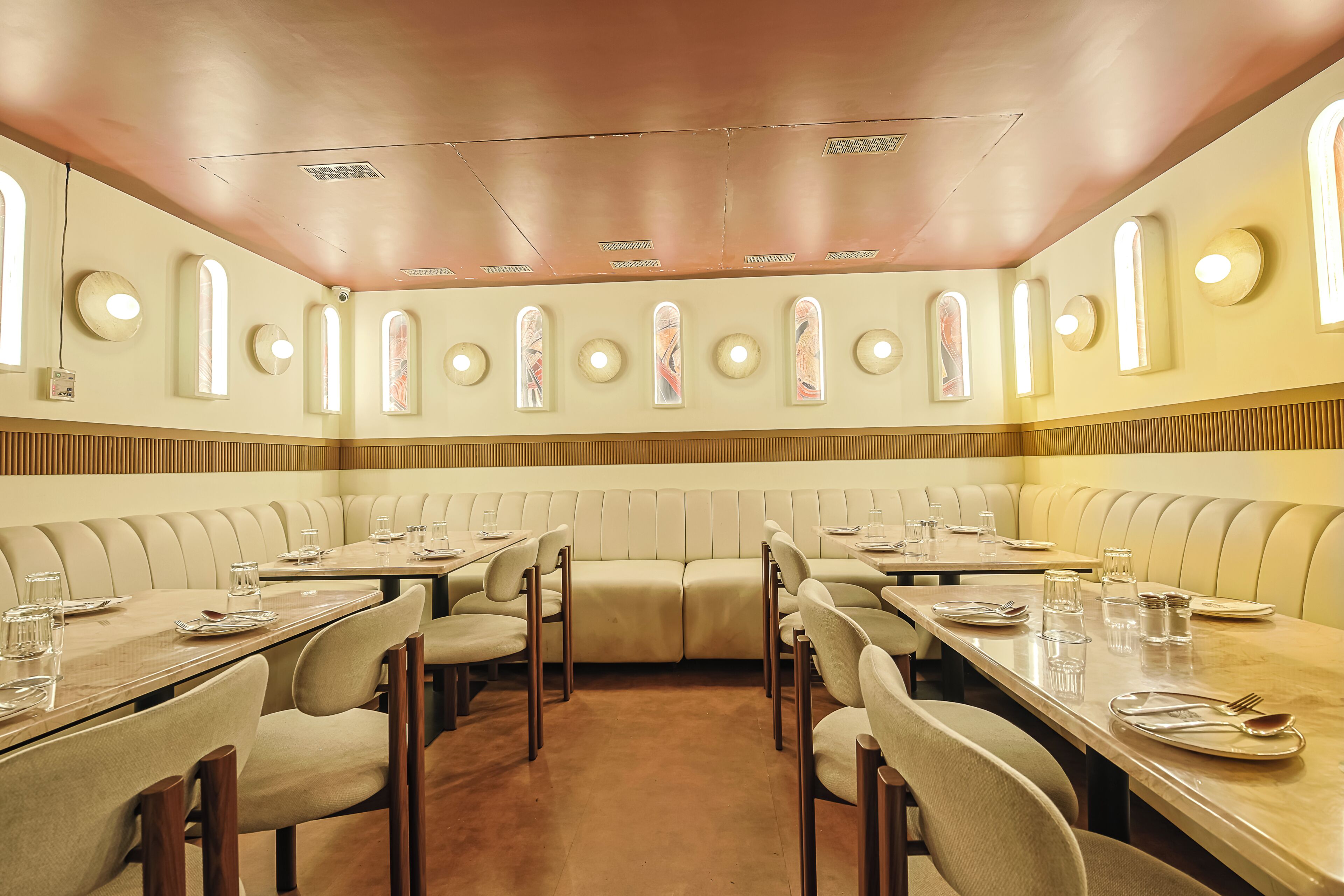 Un restaurant avec des banquettes et des tables rectangulaires, équipé du nécessaire de base pour le service à table.