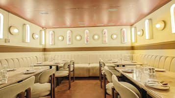 Un restaurant avec des banquettes et des tables rectangulaires, équipé du nécessaire de base pour le service à table.