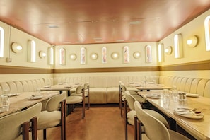 A restaurant with booth seating and rectangular tables, equipped with basic table settings. - Hotel Maurya Residency (Mysore)