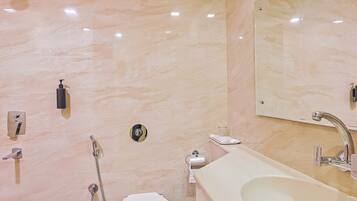 A bathroom with a toilet, bidet, sink, and mirror.