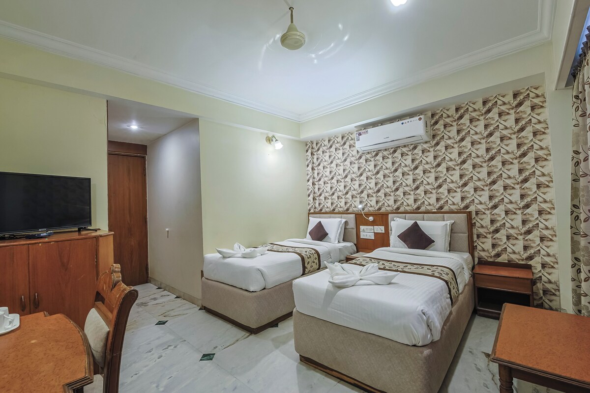 A hotel room with two beds, a TV, a desk, and a wardrobe.
