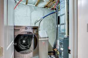 Ein Waschraum mit Waschmaschine, Trockner und verschiedenen Sanitärrohren.