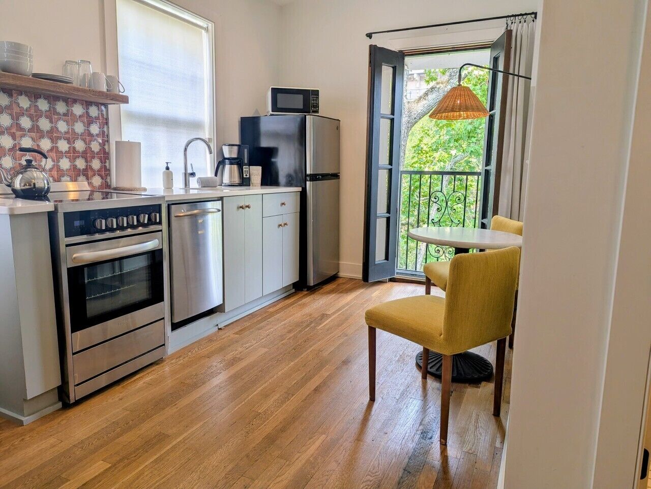 A compact kitchen with a microwave, refrigerator, oven, and sink. There's a dining area with a table and chairs.