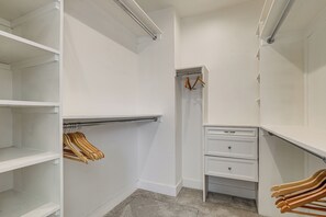 Ein begehbarer Kleiderschrank mit offenen Regalen, einer Kleiderstange und einer eingebauten Kommode.