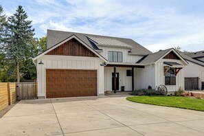 Une maison à deux étages avec un garage, un porche à l’avant et une pelouse bien entretenue.