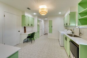 Una cocina pequeña con gabinetes verdes, una encimera blanca y un suelo estampado.