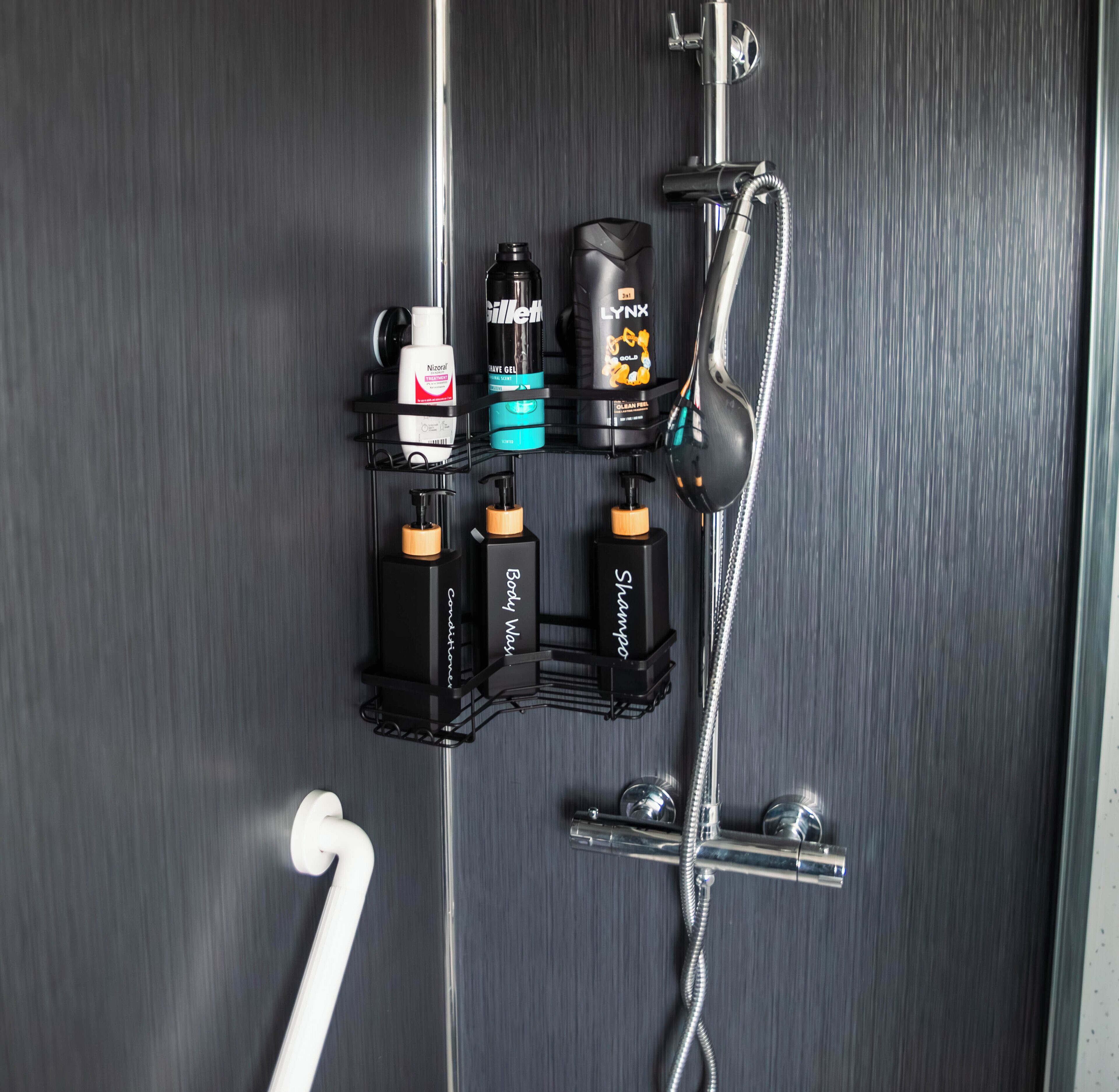 A bathroom with a shower, a towel rack, and a soap dispenser.