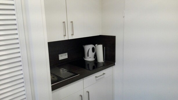 A kitchenette with a black countertop, a kettle, a coffee maker, and a trash bin. - Cozy one-room apartment right on the market square and next to the spa gardens (Grömitz)