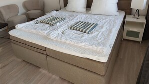 A neatly made bed with a striped pillow, a bedside lamp, and a nightstand with a drawer. - Cozy one-room apartment right on the market square and next to the spa gardens (Grömitz)