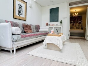 En moderne stue med en hvid sofa, et lille sofabord og en hvid måtte.