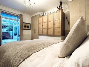 A bedroom with a bed, a wardrobe, and a view of the outside. - Kensington Garden Sanctuary - birds, squirrels & unique art! By Holland Park (Greater London)