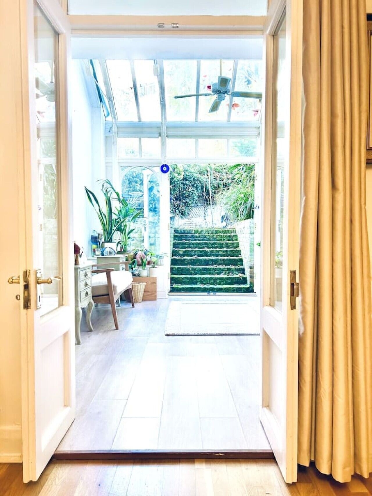 An open door leading to a room with a desk, chair, and potted plants.