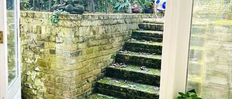 A staircase leading to a garden area with outdoor furniture and a statue.