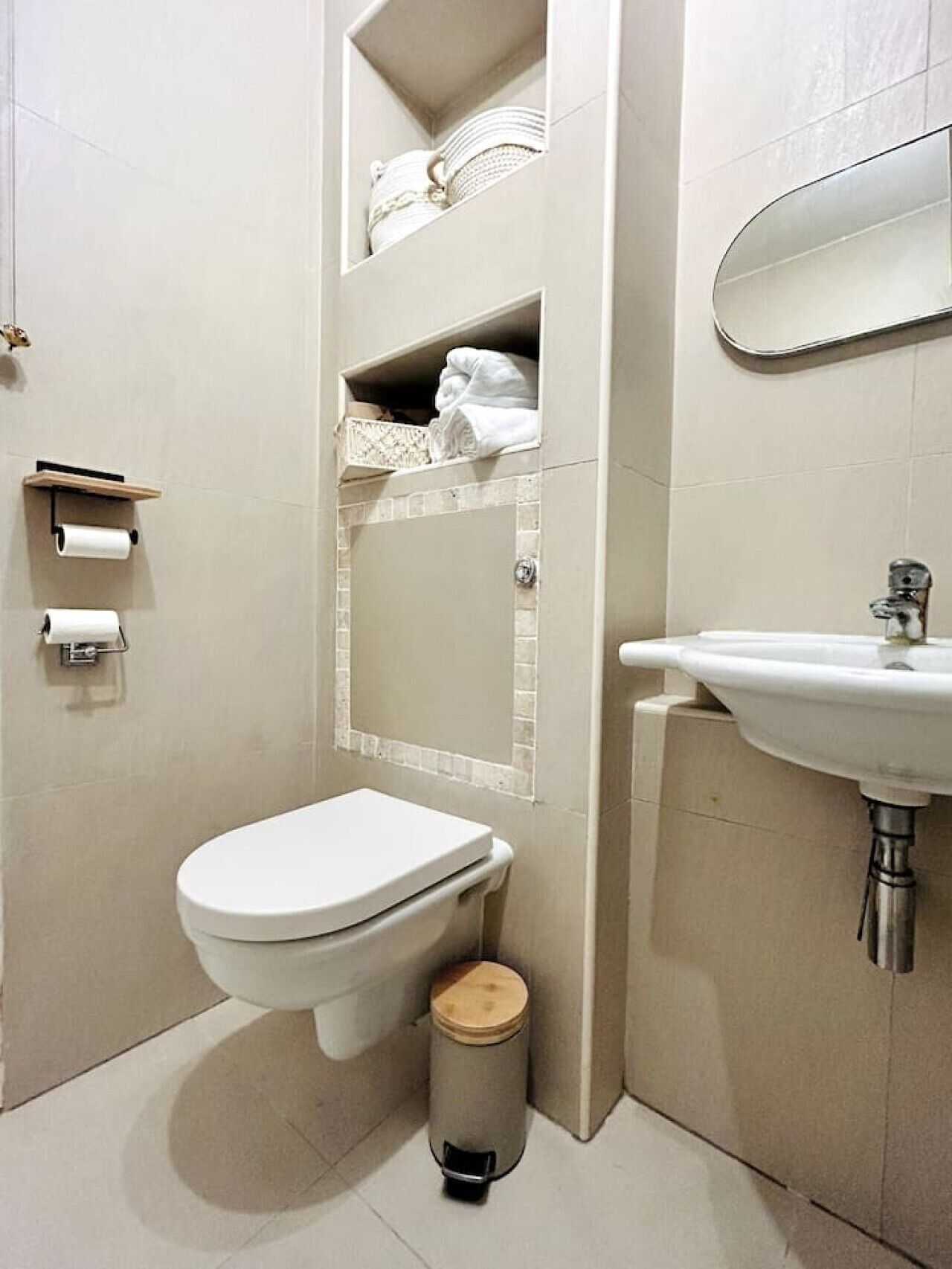 A bathroom with a toilet, sink, and a small trash can.