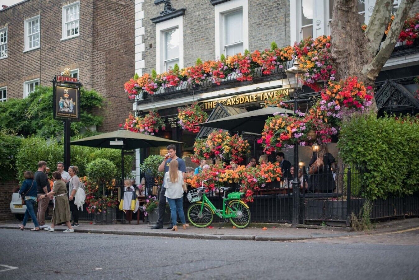 A pub with a traditional facade, outdoor seating, and a bicycle parked outside.