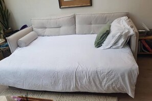 Ein großes Bett mit weißer Bettdecke und zwei Kissen, ein Nachttisch mit Lampe sowie ein gerahmtes Bild an der Wand.