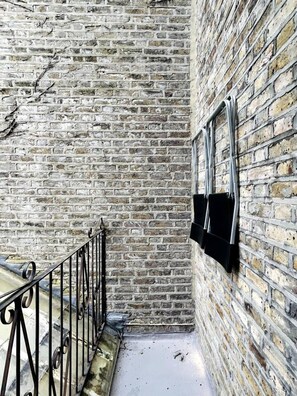 A narrow brick corridor with a metal railing on one side and a window on the other. - Kensington Deluxe Suite: 1-bedroom home in London - A Grand Stay (Greater London)