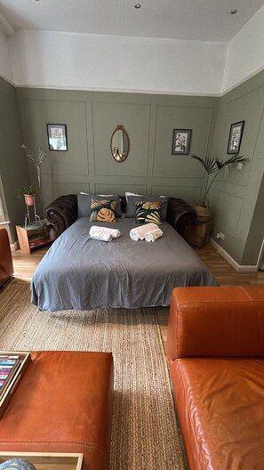Un dormitorio con una cama, dos almohadas, una mesita de noche, un espejo y una planta en maceta.
