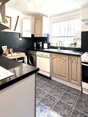 A kitchen with a washing machine, a sink, and cabinets. - Kensington Deluxe Suite: 1-bedroom home in London - A Grand Stay (Greater London)
