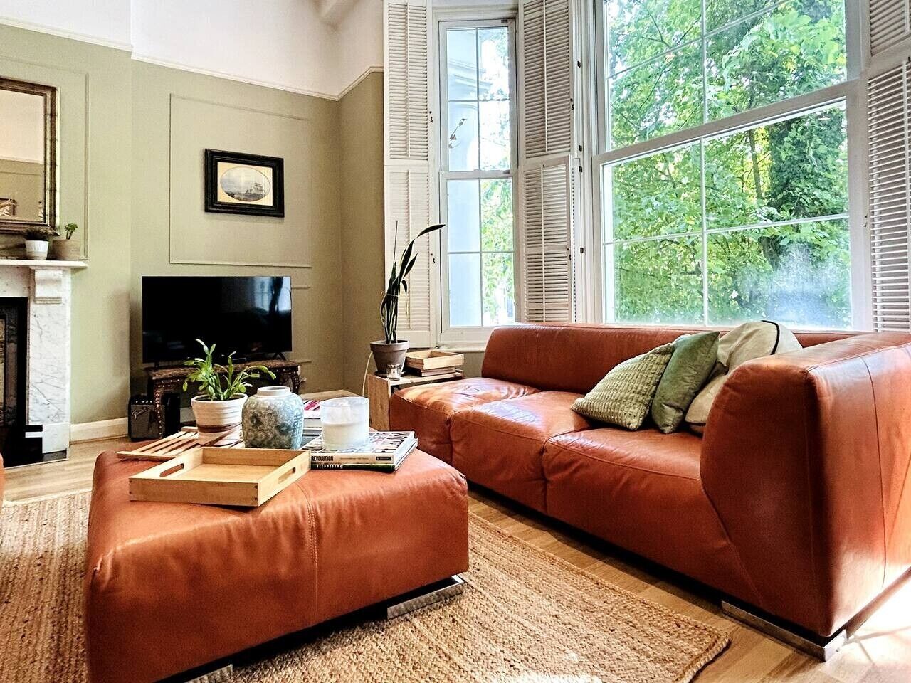 A living room with a sofa, ottoman, and a flat-screen TV.