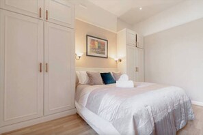 A bedroom with a bed, white curtains, and a painting on the wall. - Kensington Deluxe Suite: 1-bedroom home in London - A Grand Stay (Greater London)