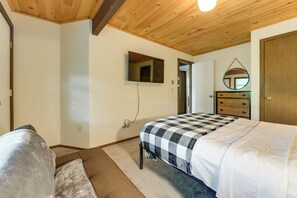 A bedroom with a bed, a dresser, a mirror, and a television on the wall.
