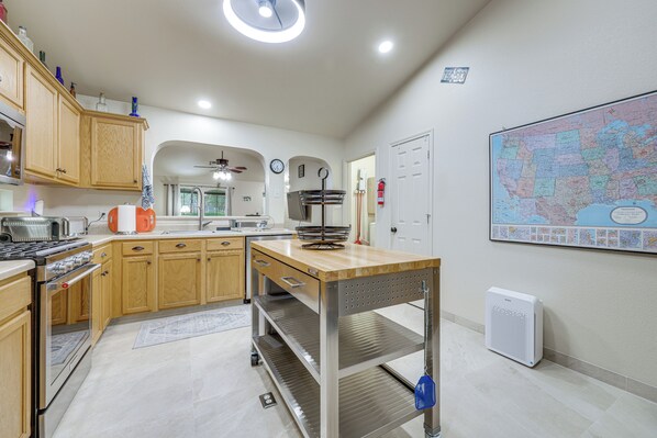 A modern kitchen with wooden cabinets, stainless steel appliances, and a central island. - Between Austin & San Marcos! Family Home (Kyle)